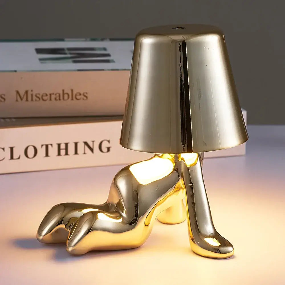 Gold-colored glossy metallic man table lamp shaped like a reclining high-heeled shoe with inverted conical shade night light