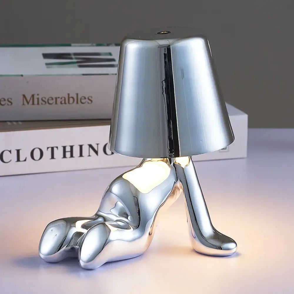 Articulated golden man table night light with shiny silver high-heeled shoe-shaped lamp and conical shade