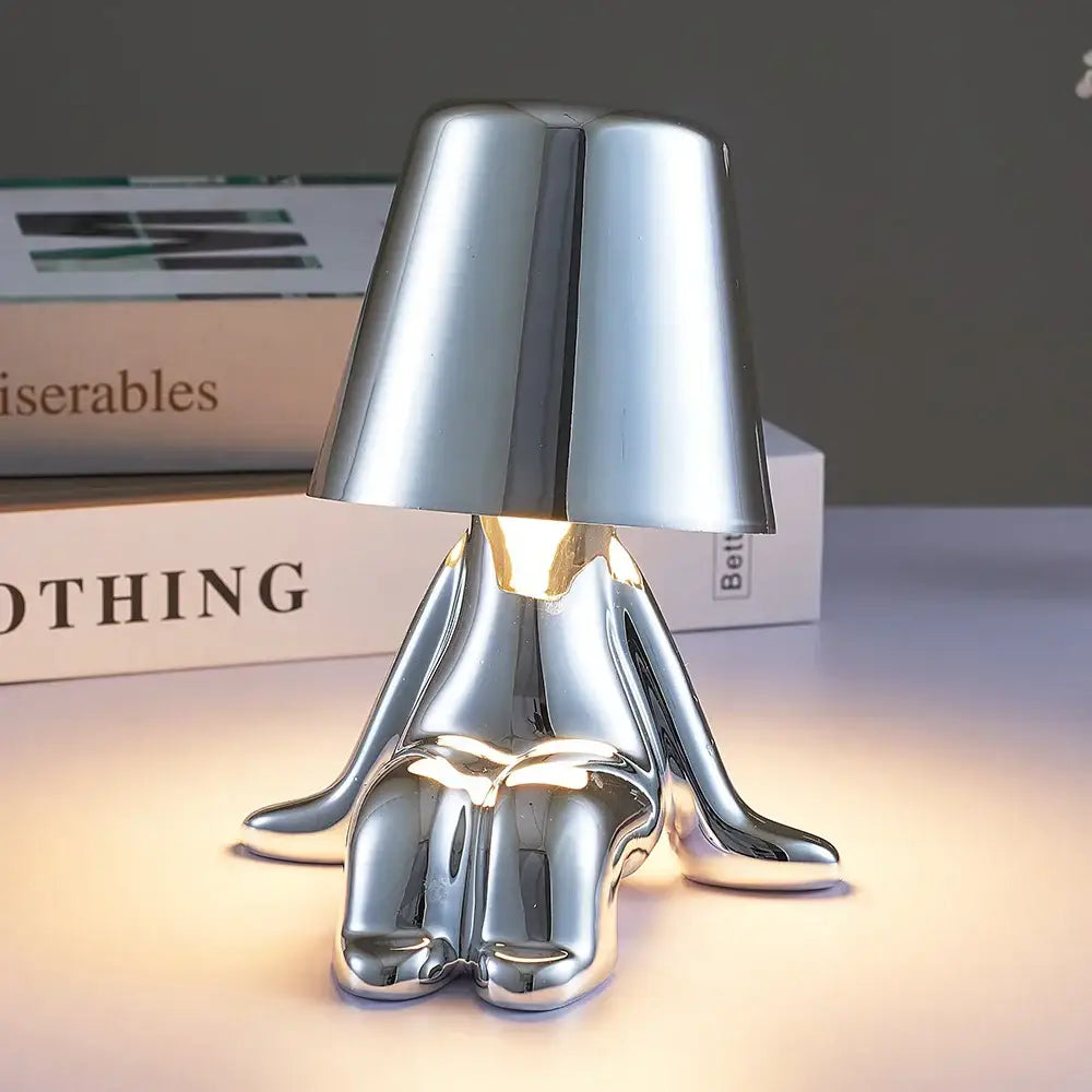 Silver metallic man table lamp shaped like a seated figure with illuminated base perfect as a night light