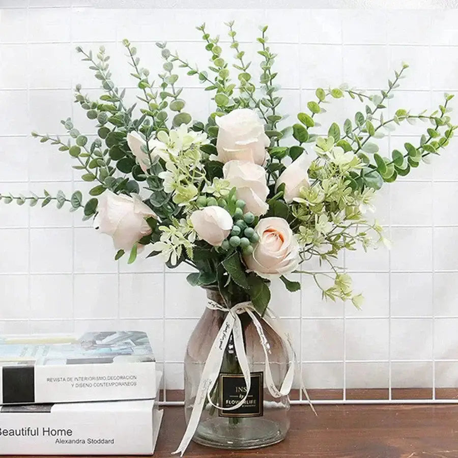A delicate arrangement of artificial white roses and eucalyptus greenery stems in a clear glass vase for living room decor