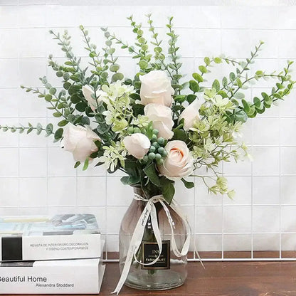 A delicate arrangement of artificial white roses and eucalyptus greenery stems in a clear glass vase for living room decor