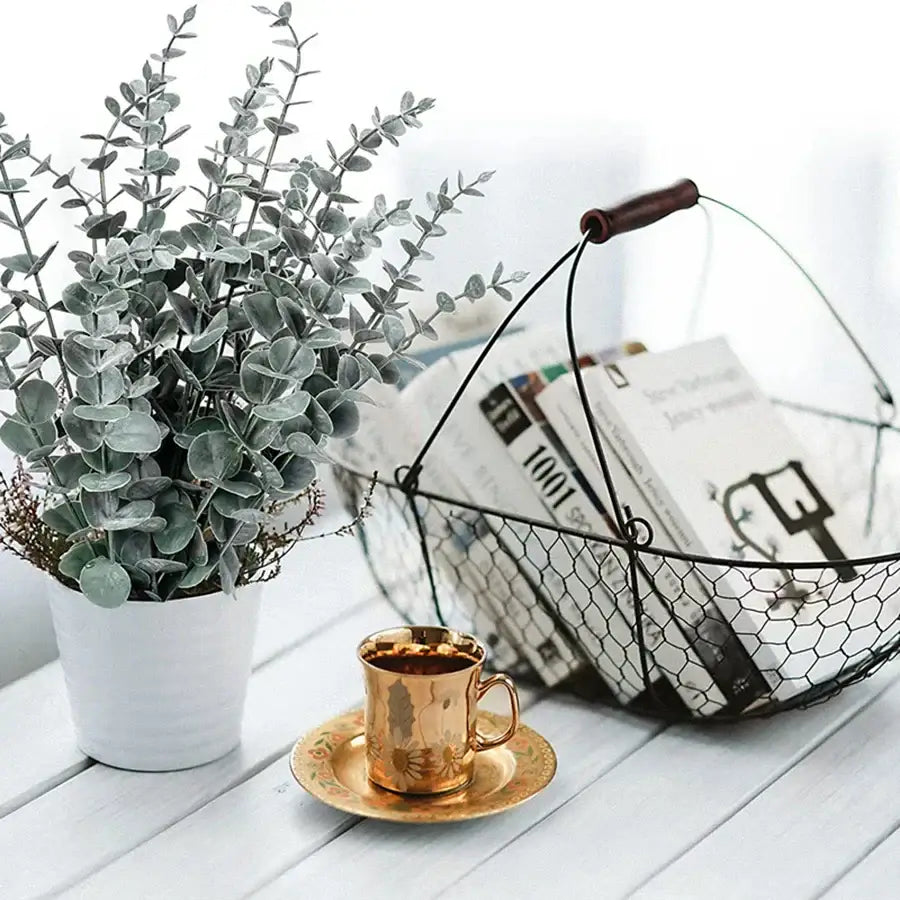 Gold-toned ceramic coffee cup with floral embossing on matching saucer for decorbites artificial eucalyptus leaves decor