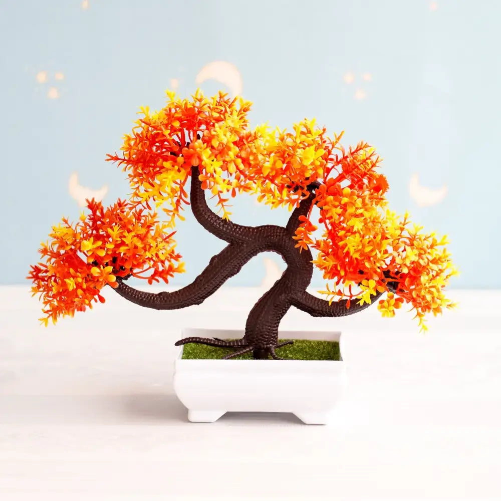 Artificial bonsai tree with vibrant orange and yellow leaves in a white ceramic pot with green faux moss for decor