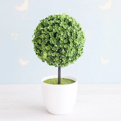 A lush artificial bonsai tree with green foliage and pink accents in a white ceramic pot for garden decor