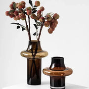 Artisan glass vase featuring a sleek amber-tinted glass with a bulbous midsection and dark base for elegant decor