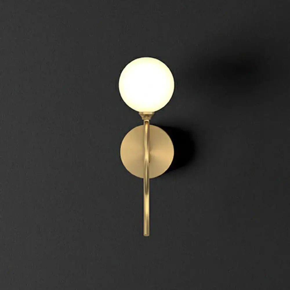 Artistic gold spherical wall lighting fixture with frosted glass globe and minimalist metallic base for bedroom use