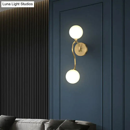 Artistic gold wall lighting fixture with two milky glass spherical shades for bedroom wall sconce lighting