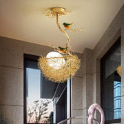 Golden bird-themed ceiling light with milk white glass ball and hand-sewn aluminum nest in decorbites artistry pendant