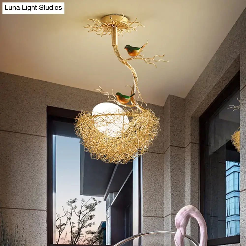 Golden chandelier pendant featuring artistry milk white glass ball with bird-themed branches and hand sewn aluminum nest