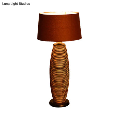 Lámpara de escritorio pequeña Asia Wood con luz de trabajo ovalada, color café y pantalla cilíndrica de tela.