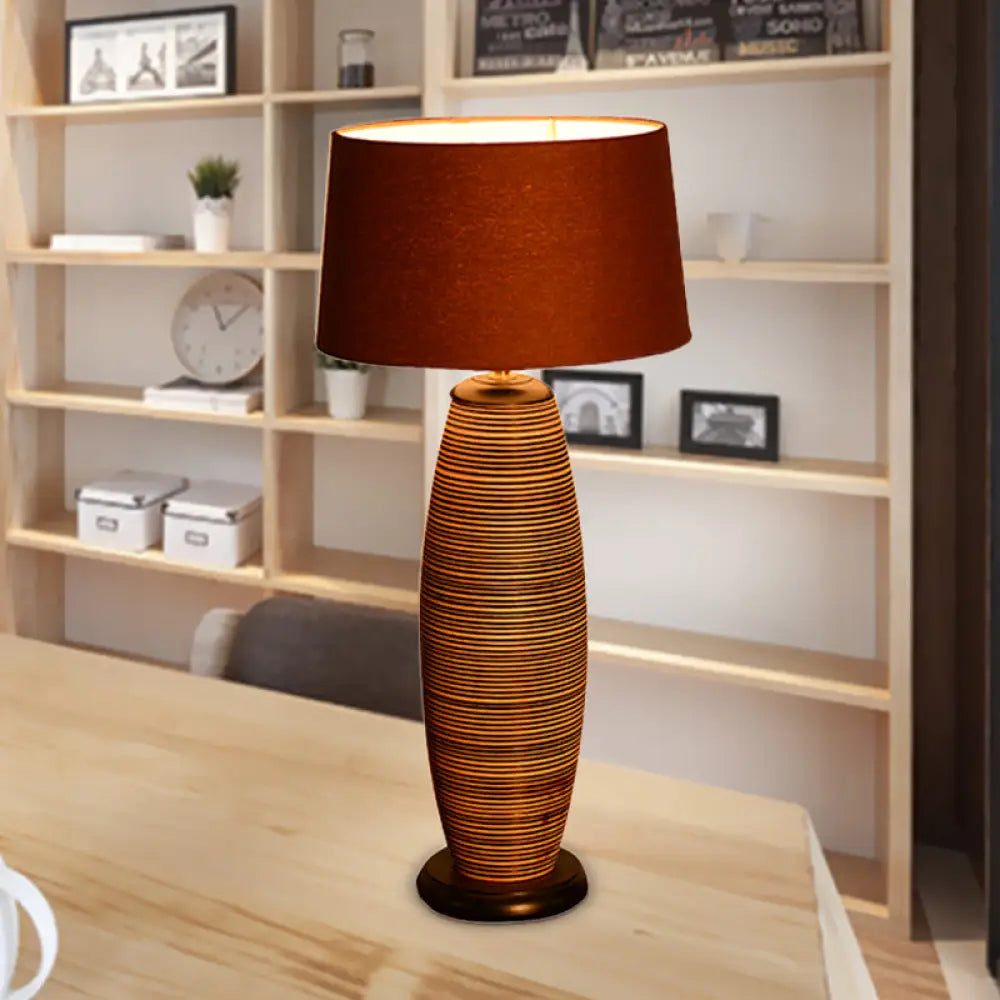 Lámpara de escritorio pequeña Asia Wood con luz de trabajo ovalada, color café y pantalla cilíndrica de tela.