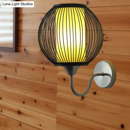 Asian style black bamboo wall lamp featuring a black wireframe spherical wall light with a warm yellow illuminated panel and gooseneck arm