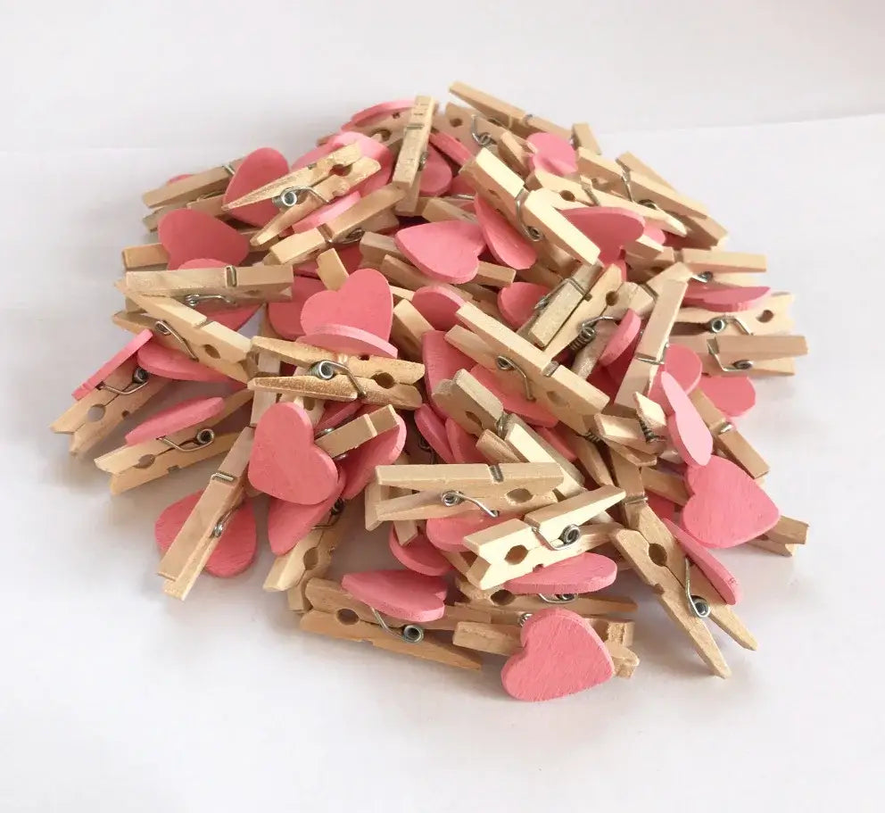 Assorted pink heart-shaped mini wooden clips with natural wood accents and metal springs for bedroom photo decor