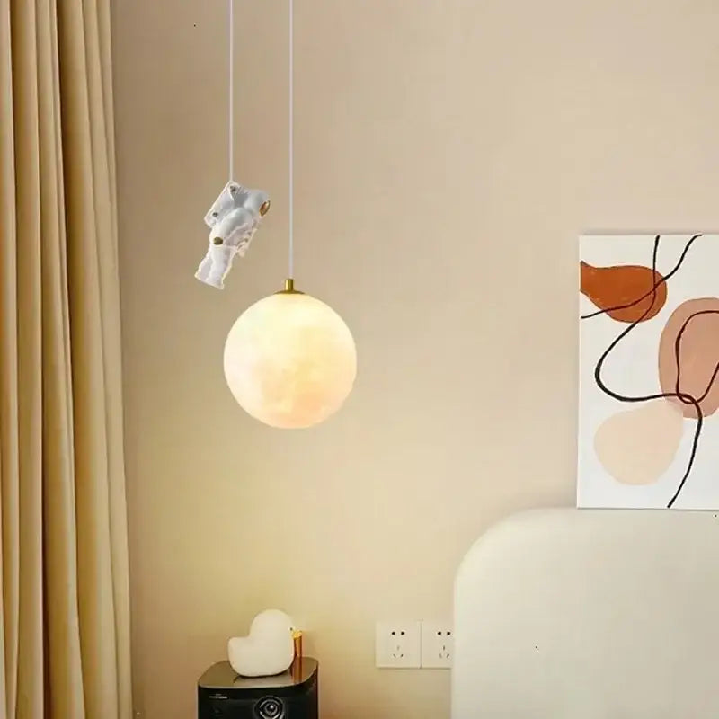 White ceramic astronaut moon led pendant light with gold accents and glowing spherical lampshade for bedroom