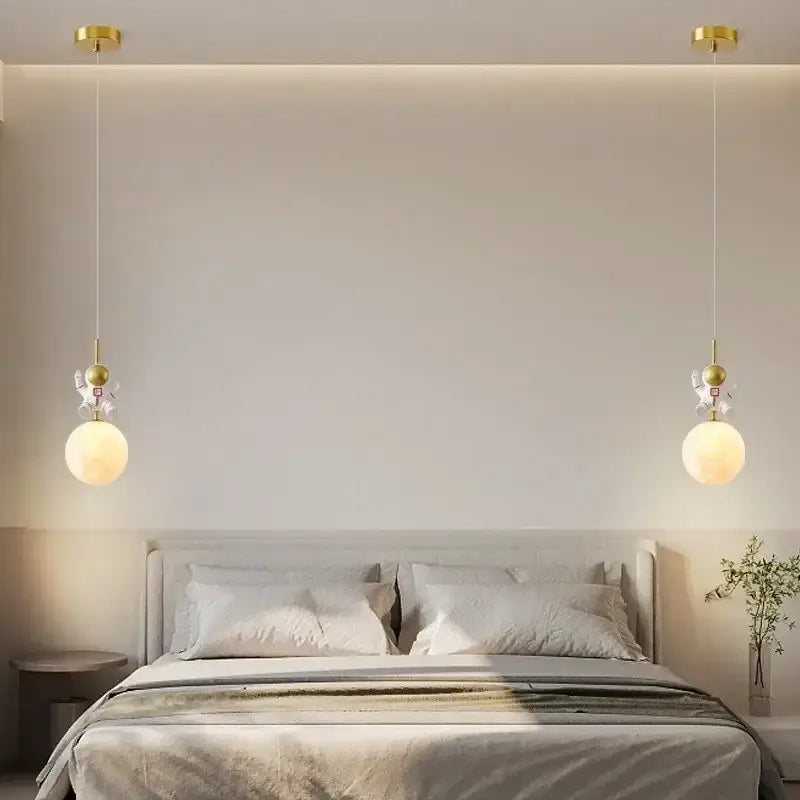 Gold-finished astronaut moon white and gold led pendant light with spherical glass shades above a bedroom bed
