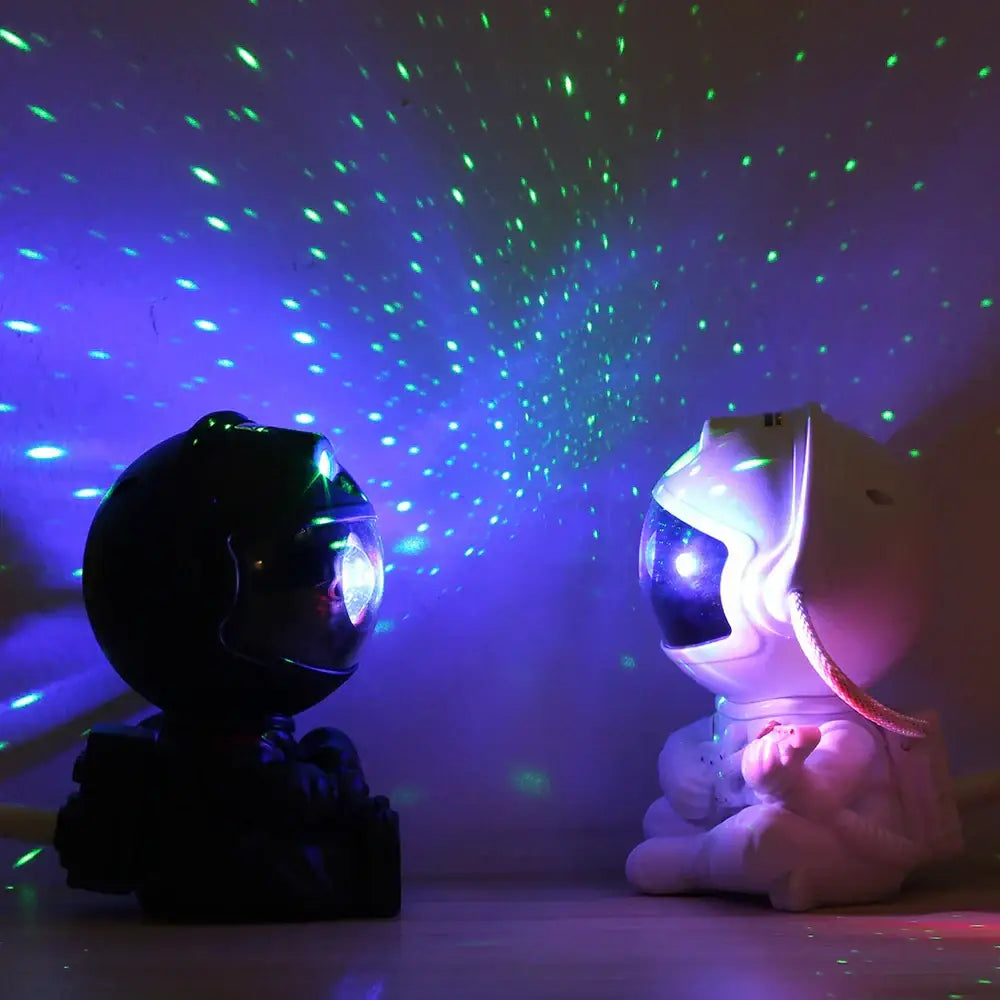 Two astronaut-themed led galaxy star night light projectors in black and white with pink, casting colorful starlight decorbites galaxy star patterns