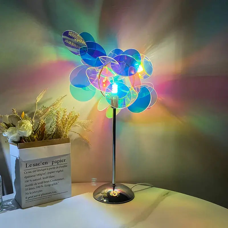 A modern aurora acrylic projection lamp with slender metallic stand and blue and green translucent discs for bedroom use