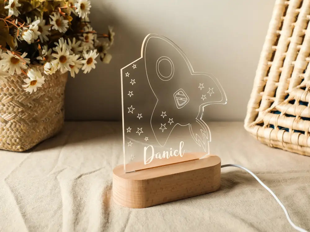 Clear acrylic rocket-shaped personalized children night light with engraved stars and name daniel on wooden base