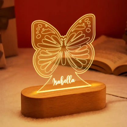 A warm glowing butterfly shaped led night light with a personalized children name engraved on its wooden base