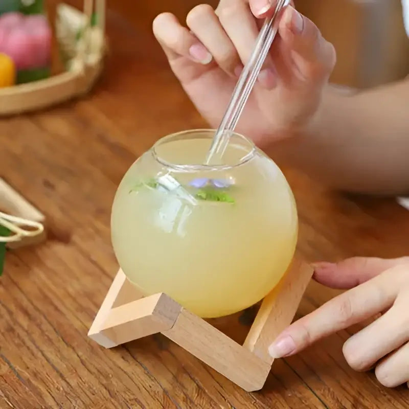 Clear glass ball shape coffee juice cocktail glass with wooden stand and straw for dining room decor