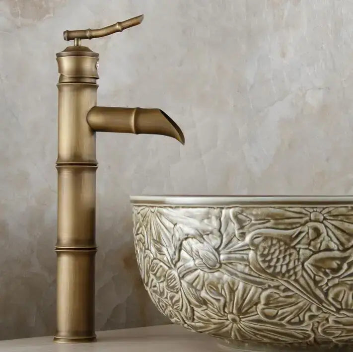 Antique brass bamboo-style basin mixer tap with sleek segmented design and curved spout for bathroom basins
