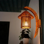 Warm-toned brown bamboo wall light fixture with vertical slats and arched bracket for bedroom use