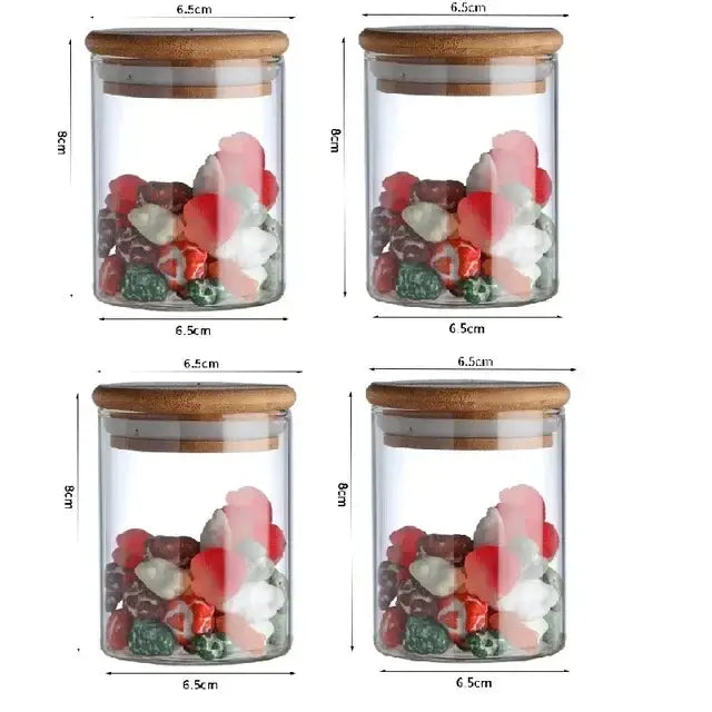 Clear glass food storage jars with bamboo lids holding colorful candies labeled for kitchen spice use