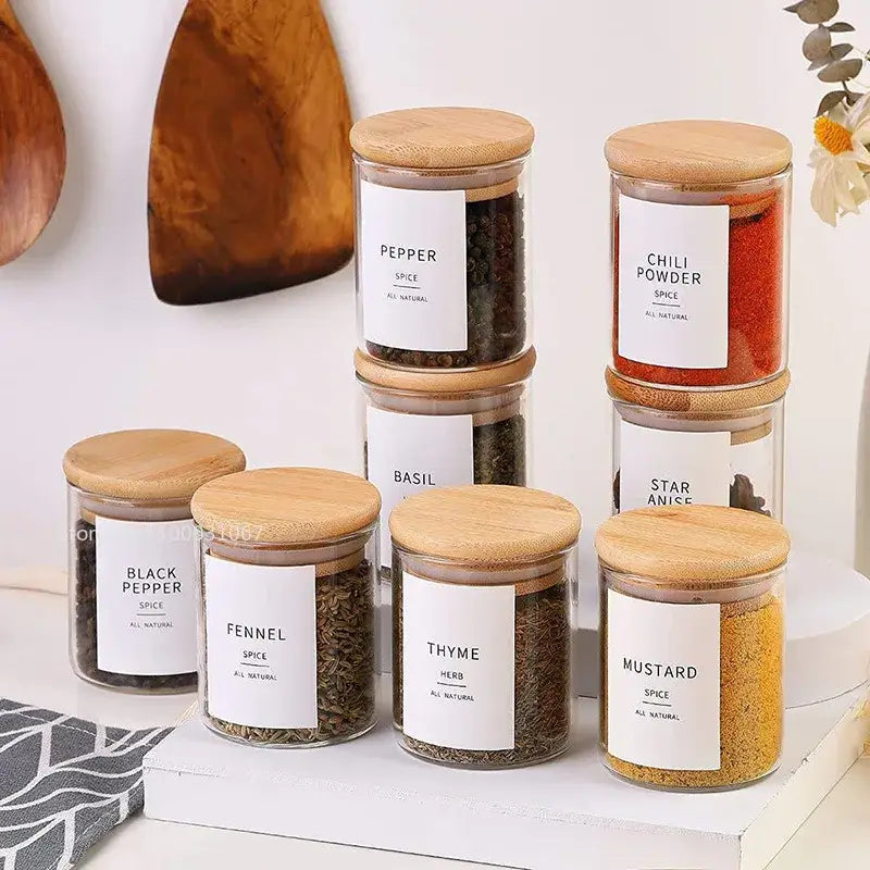 Clear glass food storage jars with bamboo lids and white labels for kitchen spice organization and food storage