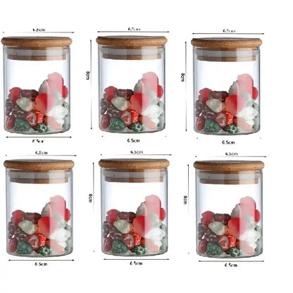 Six clear glass food storage jars with bamboo lids filled with colorful candies for kitchen spice organization