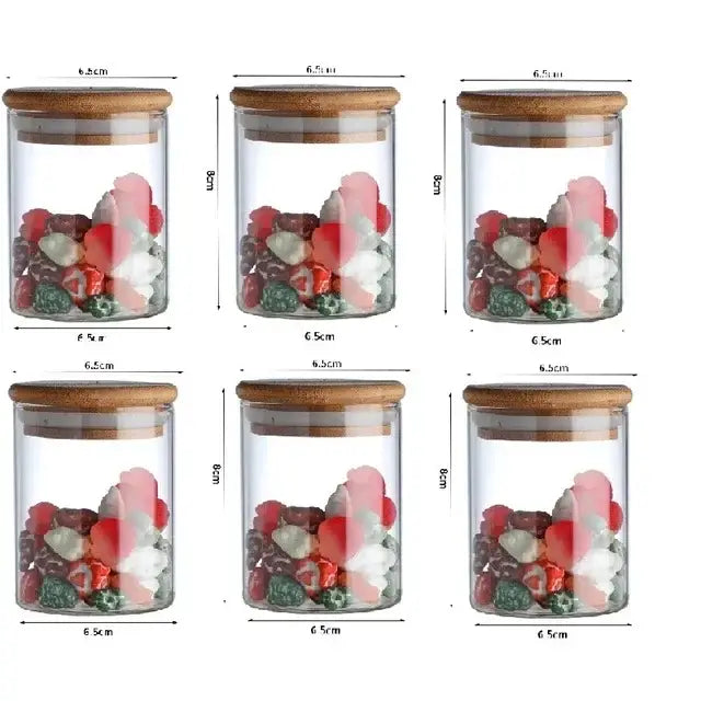 Six clear glass food storage jars with bamboo lids filled with colorful candies for kitchen spice organization