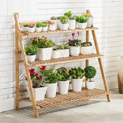 DecorBites™ bamboo light brown a-frame shelf stand with three slatted tiers holding white ceramic plant pot shelf