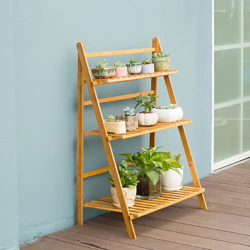Light brown bamboo plant stand with three slatted shelves folding for indoor outdoor use by decorbites