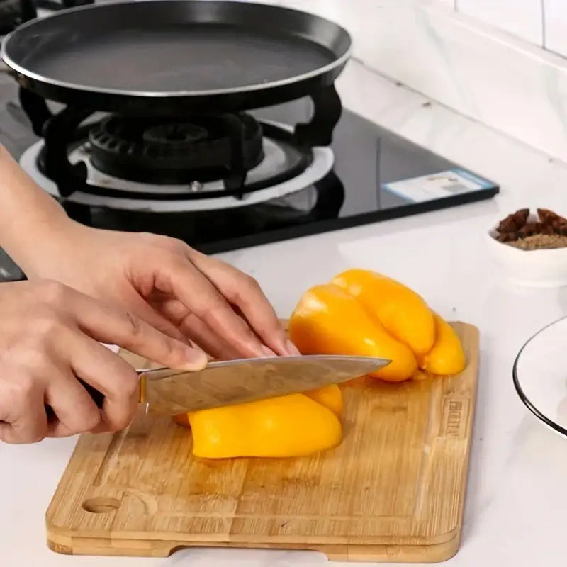 A stainless steel chef’s knife with black handle resting on a wooden board next to a decorbites bamboo seasoning box