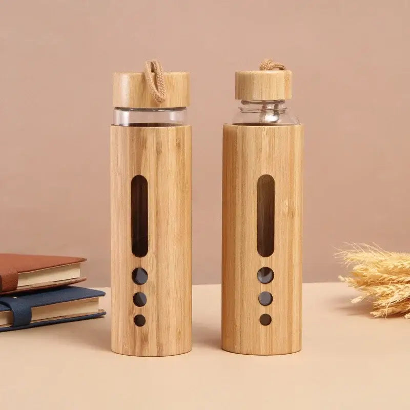 Two bamboo-wrapped glass water bottles with wooden lids and rope handles featuring vertical cutouts and circular accents