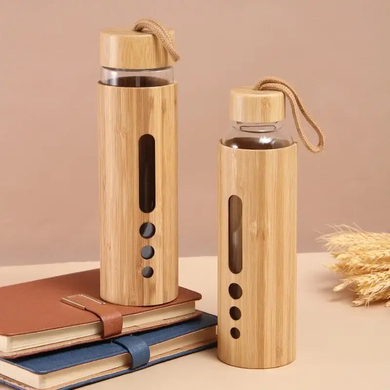 Two bamboo-finished glass water bottles with wooden caps and woven handles for kitchen and sports use