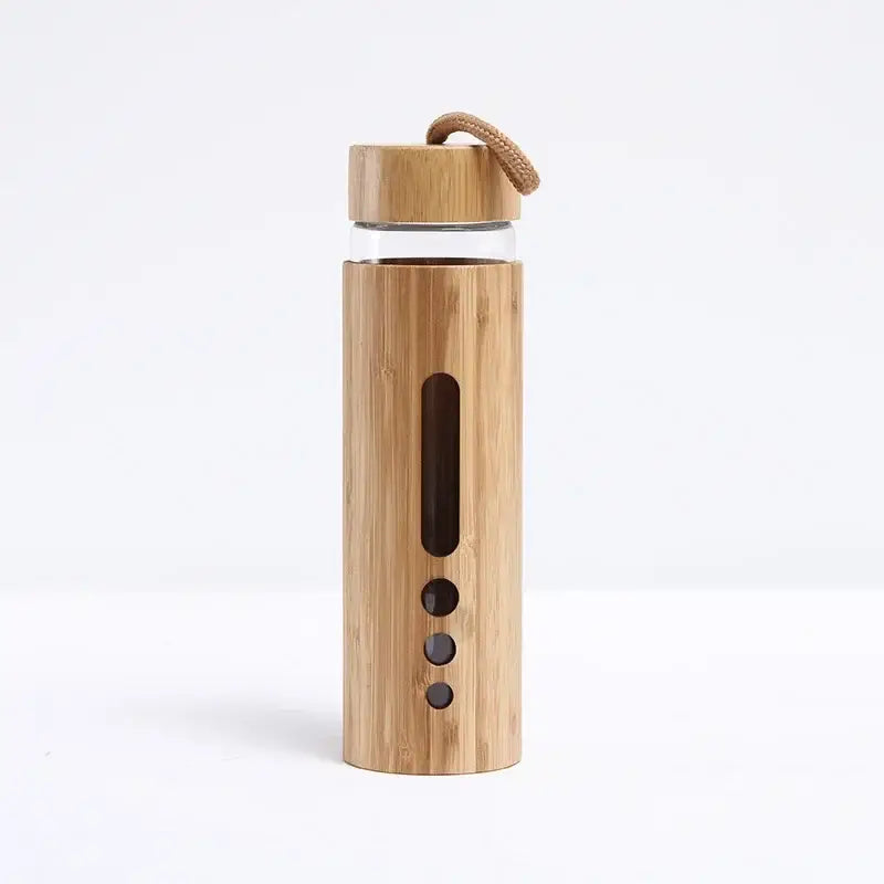 A sleek glass water bottle with a natural bamboo sleeve and lid featuring vertical slits and a rope handle