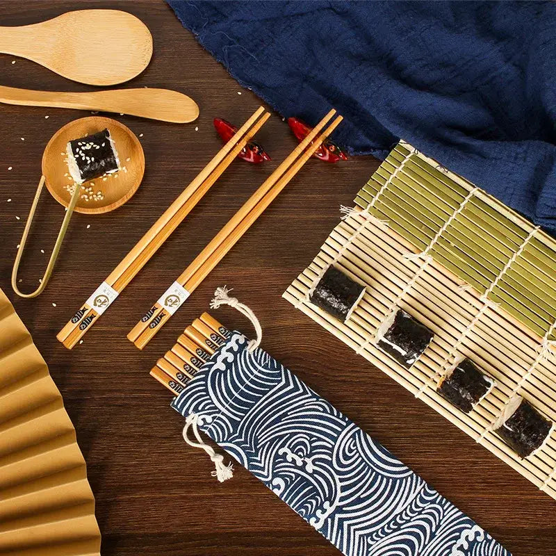Natural bamboo chopsticks with white labels arranged beside blue and white fabric pouch for sushi rolling mat and onigiri rice paddles