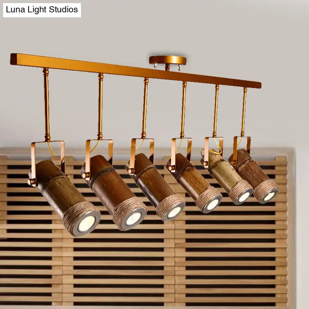 Five bamboo tube pendant led lights with brass accents and hemp rope wrapped ends hanging from gold-toned bar