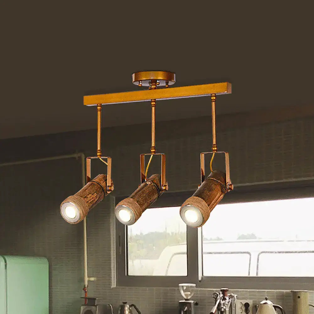 Industrial-style ceiling fixture with three rustic copper-toned led light spotlights on brass bar with bamboo tube and hemp rope