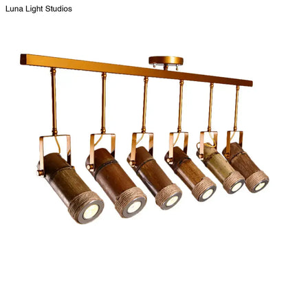 Six bamboo tube led light pendant fixtures with hemp rope and brass accents hanging from a gold-toned bar