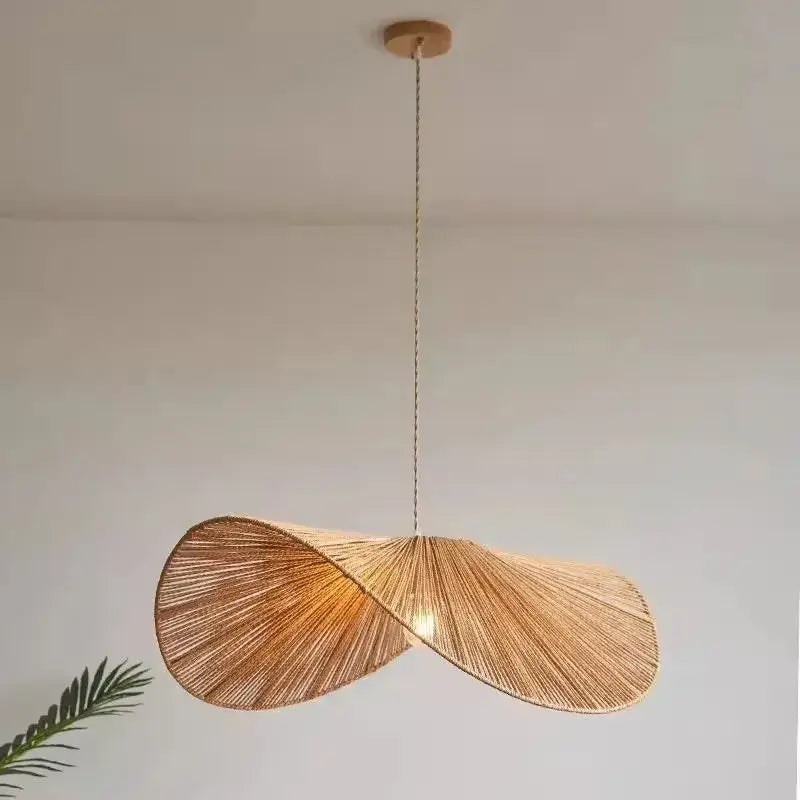 A warm-toned bamboo wabi sabi woven rattan pendant light with a twisted design hanging from a wooden mount