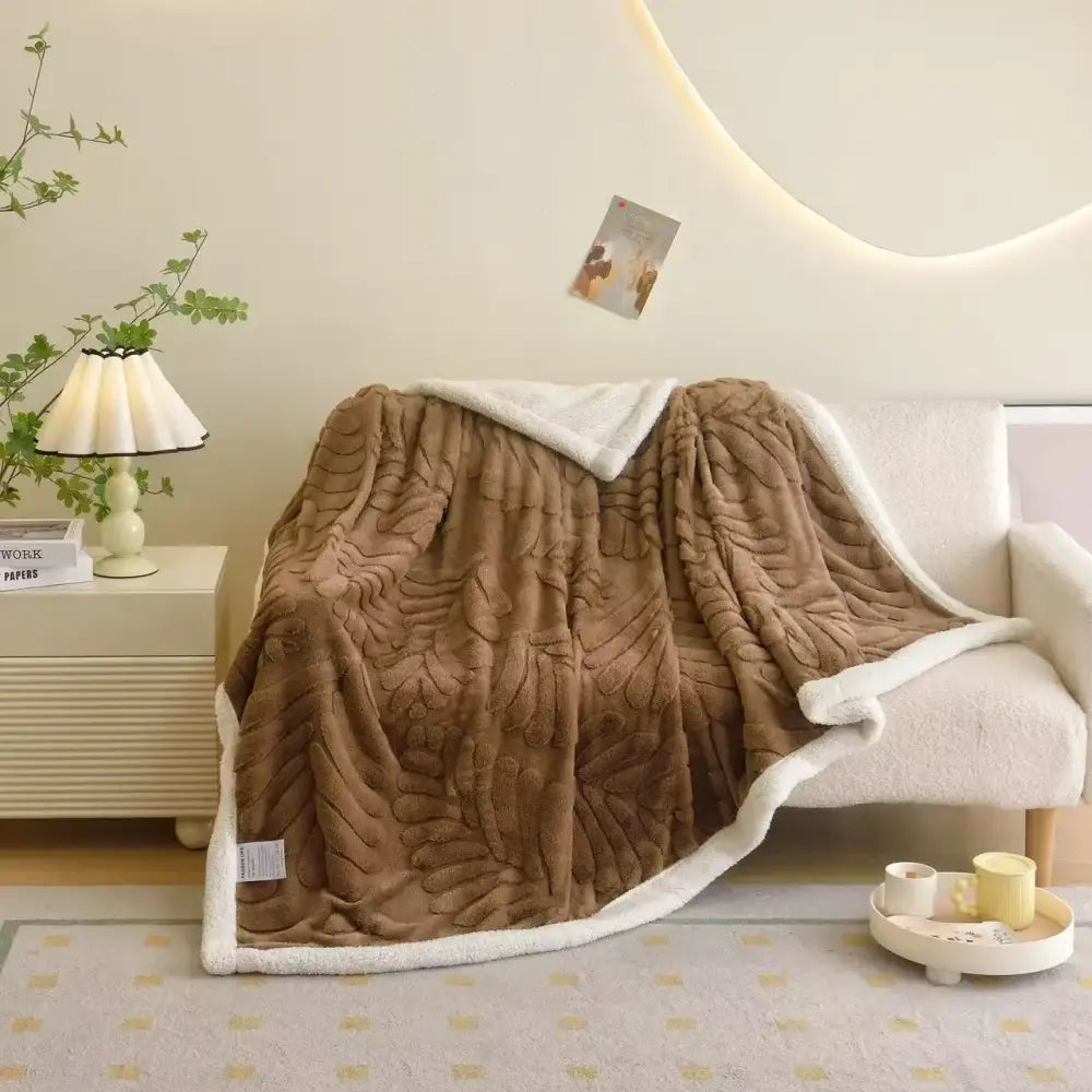 A plush brown banana leaf jacquard faux rabbit fur throw blanket with textured leaf jacquard pattern and white sherpa lining