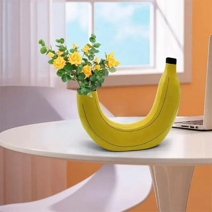 A bright yellow banana shape resin flower vase with a black cap holding yellow roses and green foliage