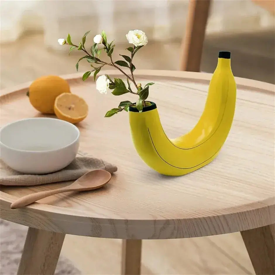 Bright yellow banana shape resin flower vase with black rim holding white flowers for decorative use
