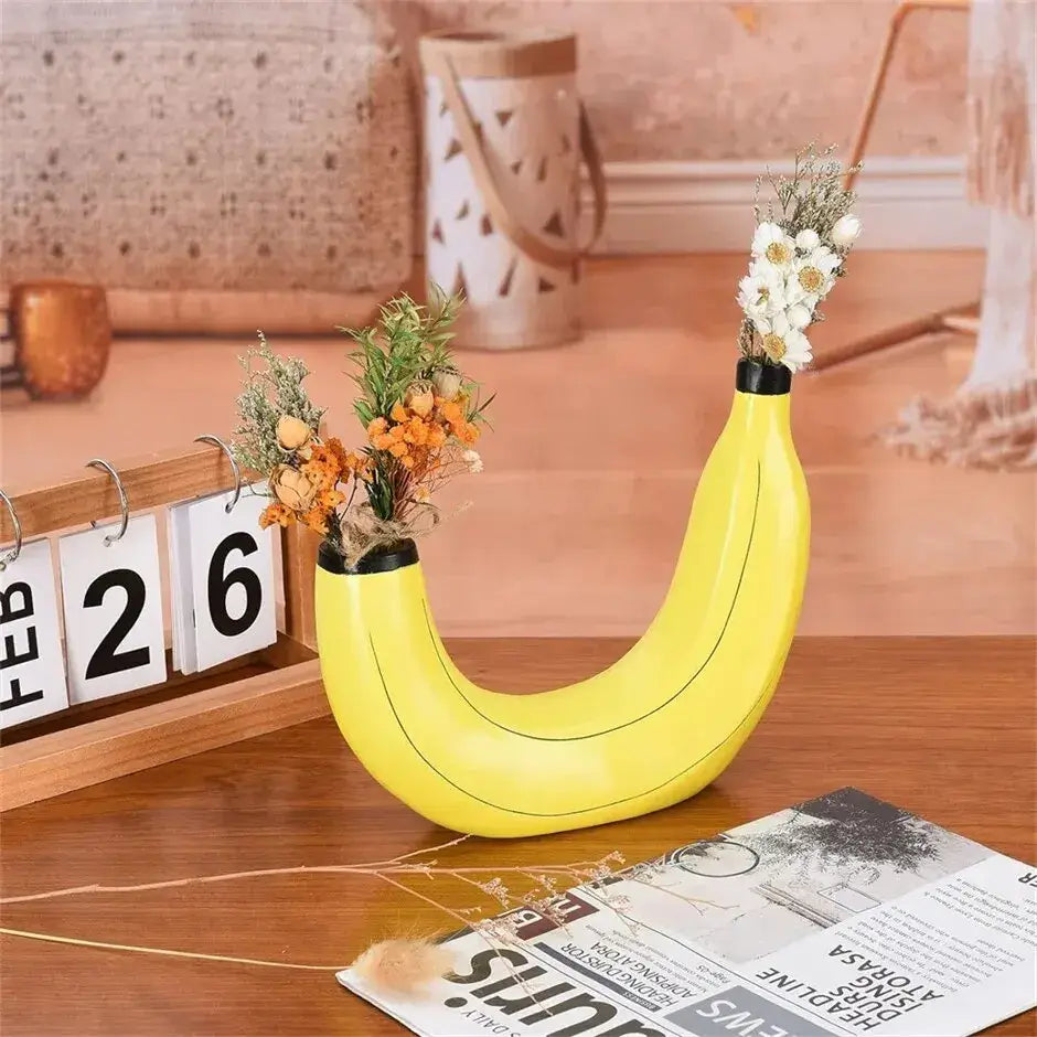 Bright yellow banana shape resin flower vase with glossy finish and black accents holding dried flowers