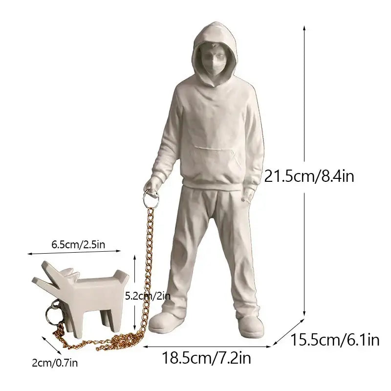 White resin banksy dog walker statue featuring a person in a hoodie holding a gold chain leash with a dog keychain