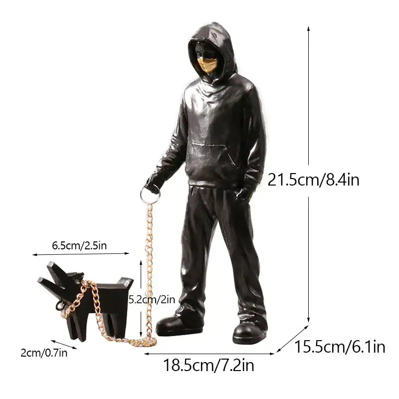 Black glossy banksy dog walker resin statue holding a gold chain leash attached to a small dog accessory