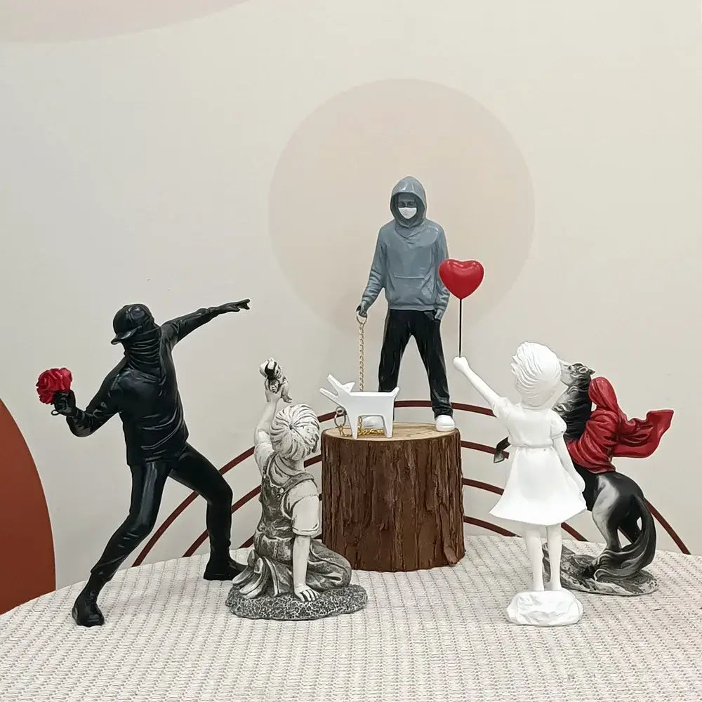 Gray hoodie-wearing banksy sculpture holding a red balloon on tree stump base from balloon girl figurines collection
