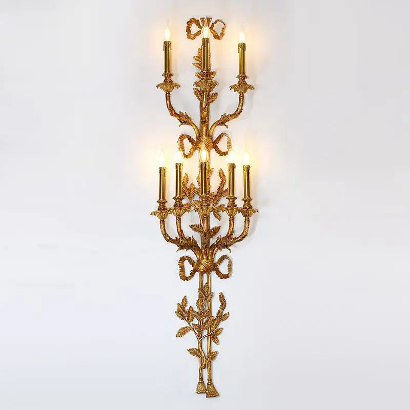 Golden ornate decorbites baroque antique brass wall sconce with intricate leaf ribbon detailing and six lit candle lights