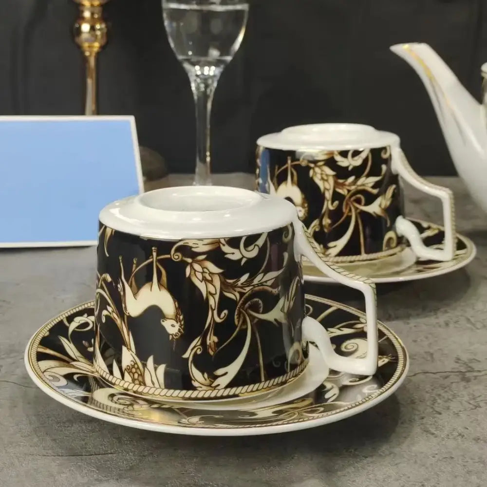 Elegant black porcelain teacup with gold ornate bird and floral patterns and matching saucer from black unicorn series
